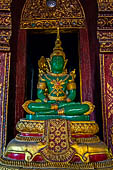 Chiang Mai - The Wat Phra Singh temple. The ubosot (ordination hall). Detail of the ku, a large ornate Buddha throne with a copy of the Emerald Buddha. 